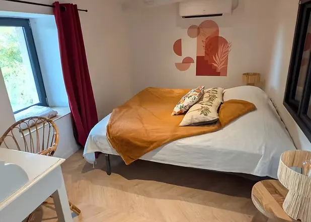 Chambre avec lit double 140 cm, couette ocre et climatisation réversible