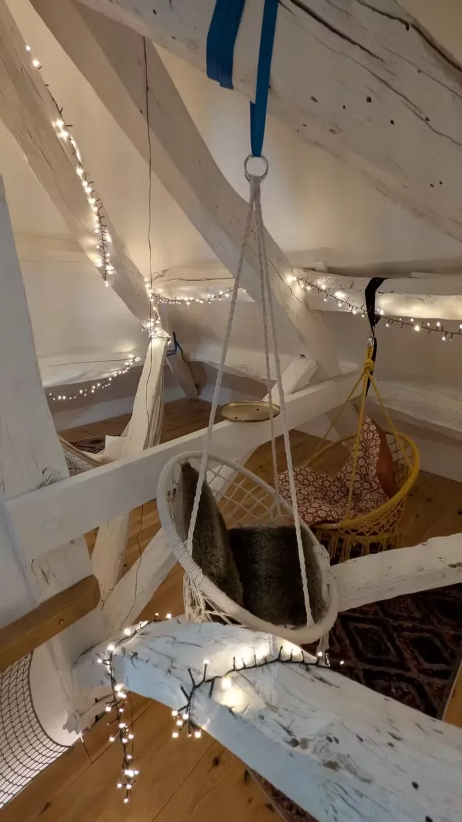 Mezzanine féerique avec poutres blanches, chaises suspendues et guirlandes étoilées