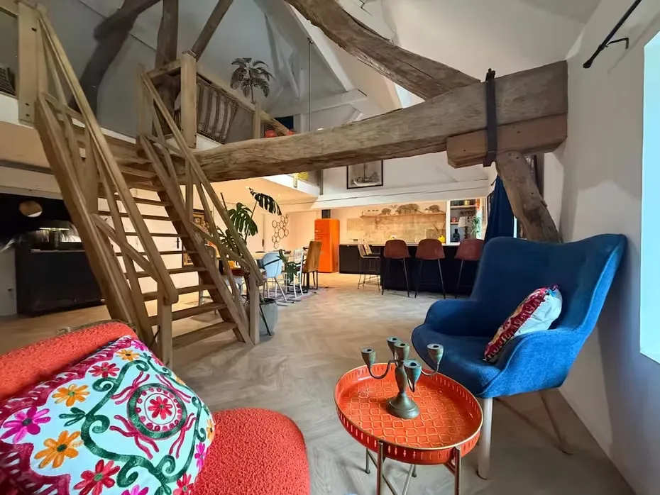 Salon du Gîte Mandarine avec poutres sablées, parquet point de Hongrie et fauteuil bleu