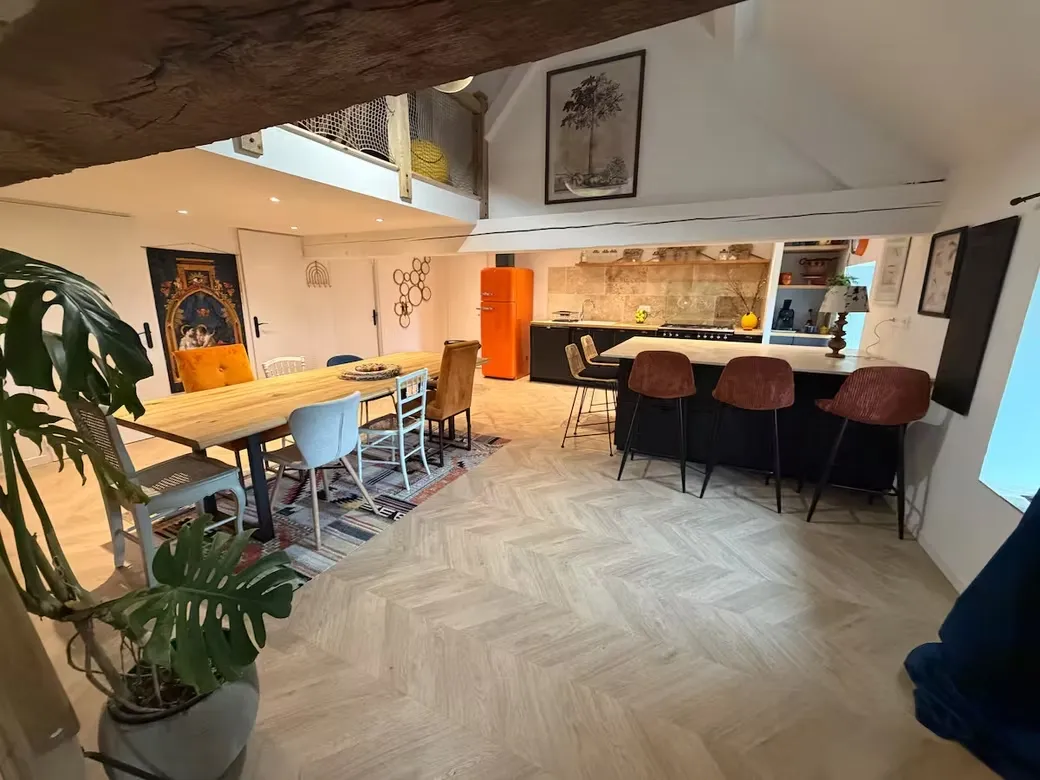 Séjour ouvert sur la cuisine avec table à manger, réfrigérateur vintage orange et poutres
