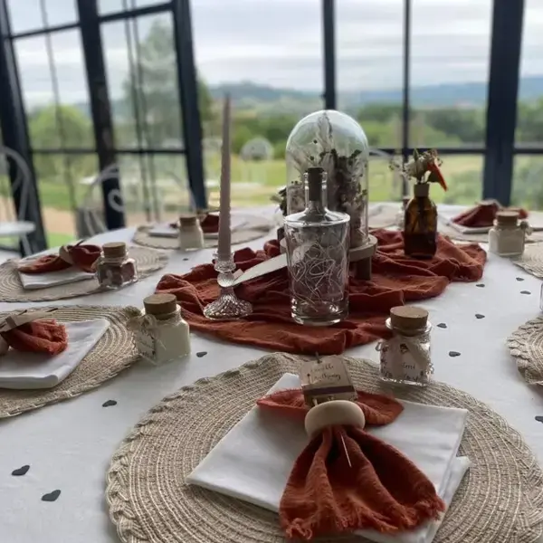Table de réception dressée avec serviettes couleur terre cuite et décorations en verre