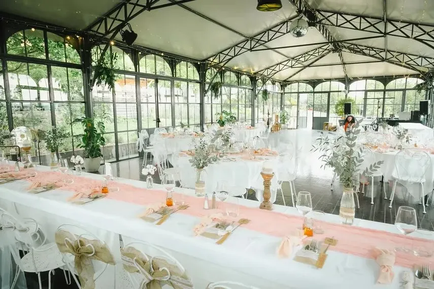Intérieur de l'Orangerie avec décoration saumon, tables longues et chaises transparentes