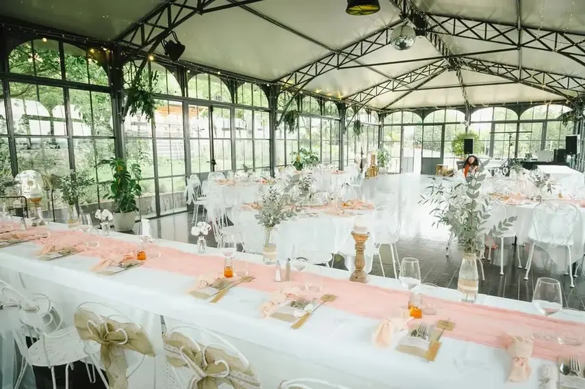 Intérieur de l'Orangerie avec décoration saumon, tables longues et chaises transparentes