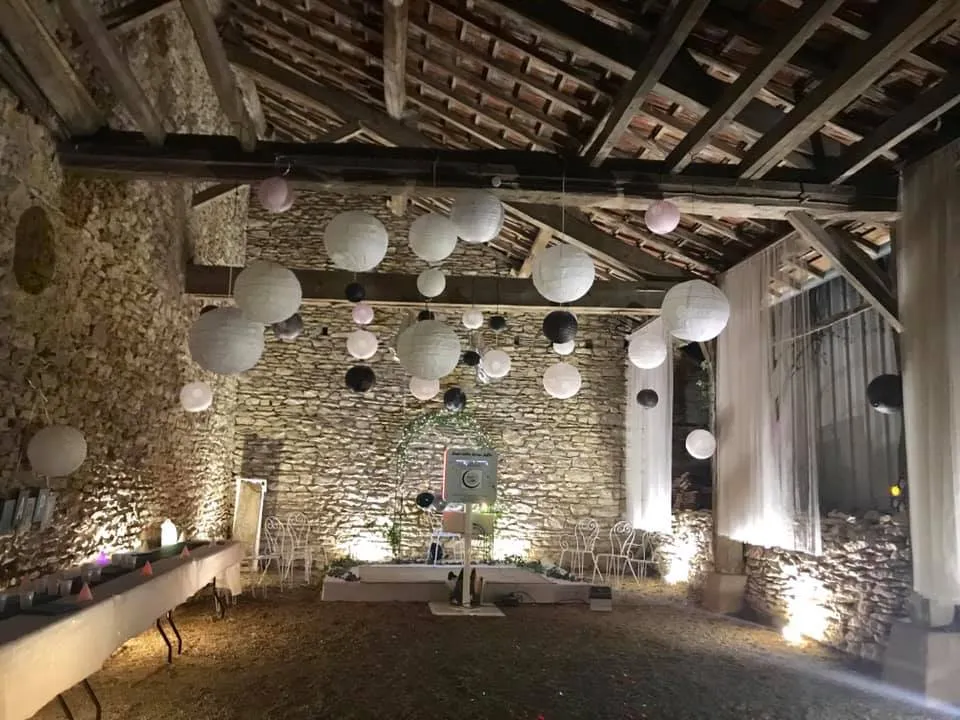 Préau en pierres aménagé avec des tables et des lanternes suspendues