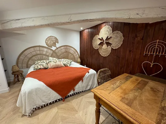 Chambre du Gîte Les Tilleuls avec tête de lit en rotin, jeté orange et parquet point de Hongrie