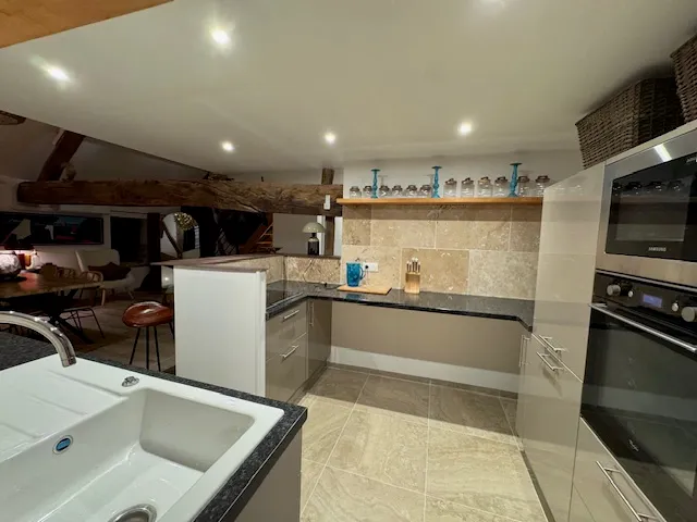 Cuisine vue d'ensemble avec évier, four encastré et plans de travail en granit