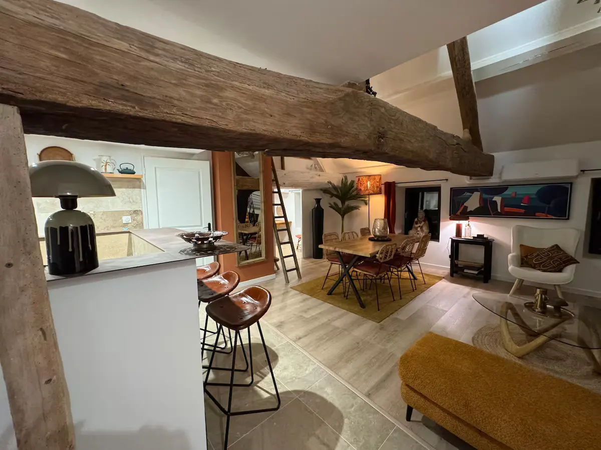 Pièce de vie d’un gîte du Domaine des Plagnes avec salon, salle à manger, cuisine ouverte et poutres anciennes.