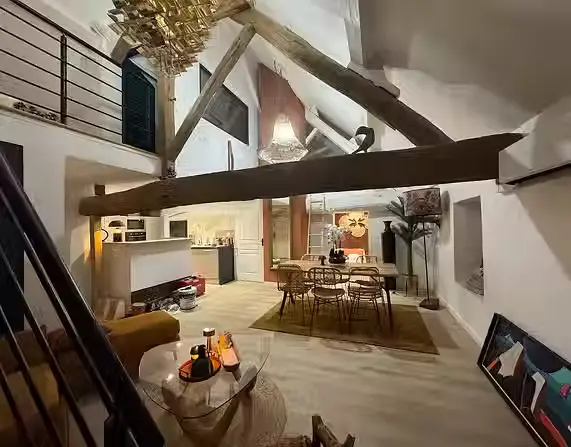 Pièce de vie avec salon, salle à manger, cuisine ouverte et poutres anciennes