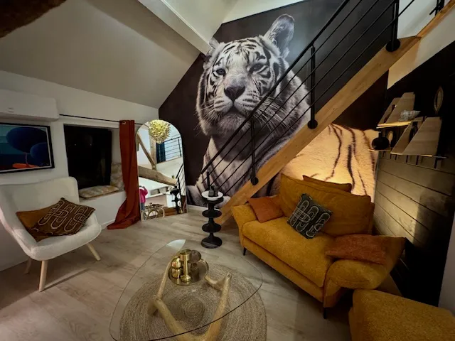 Salon du Gîte Les Tilleuls avec fresque de tigre blanc, canapé moutarde et escalier moderne