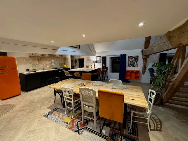 Séjour du Gîte Les Tilleuls — grande table en bois, cuisine ouverte et réfrigérateur vintage orange