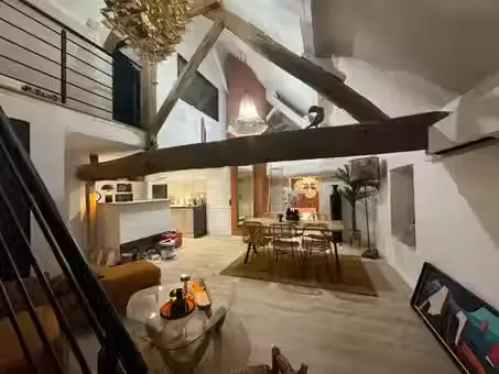 Grande pièce de vie d'un gîte du Domaine des Plagnes avec cuisine ouverte, table à manger, salon et poutres anciennes