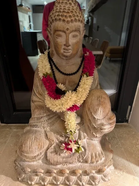 Statue de Bouddha assis ornée de guirlandes de fleurs blanches et roses